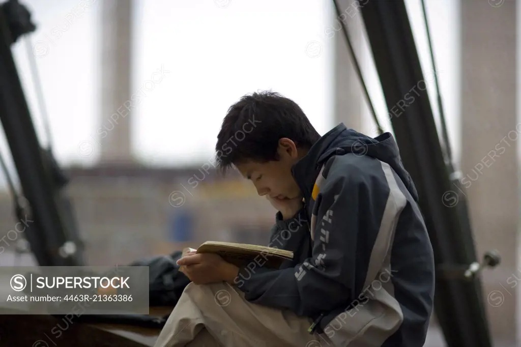 Boy sitting reading a book.