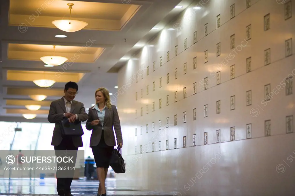 Mid-adult colleagues walking down a school corridor.