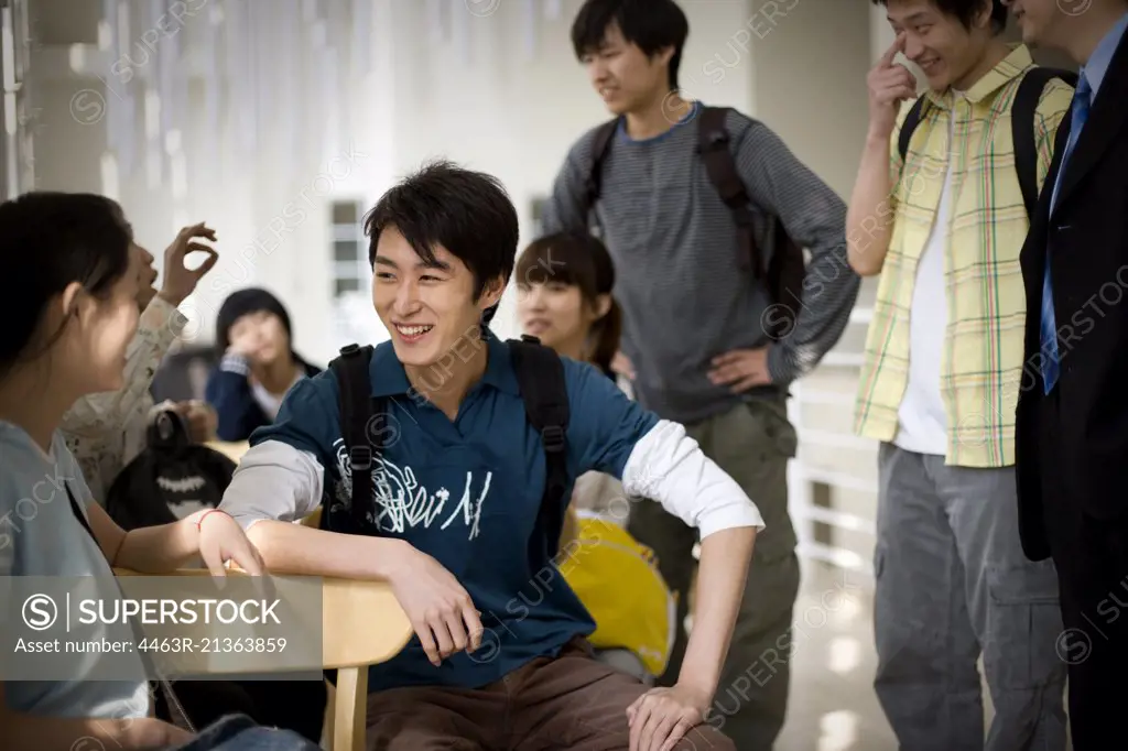 Teenage students talking with their mid-adult teacher in a classroom.