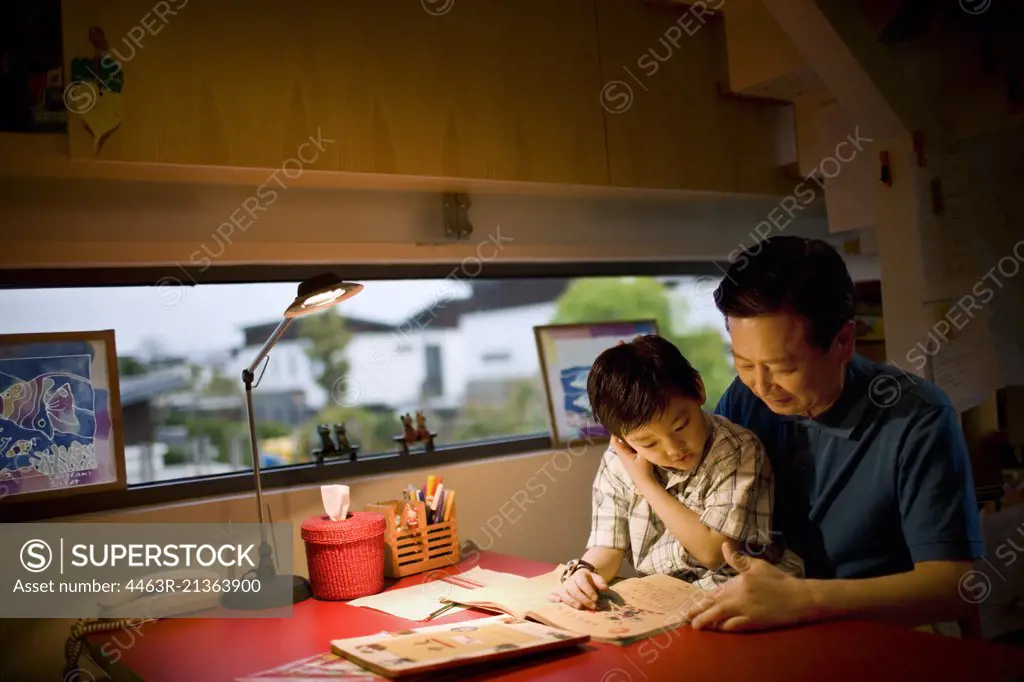 Mature man sitting reading with his son.