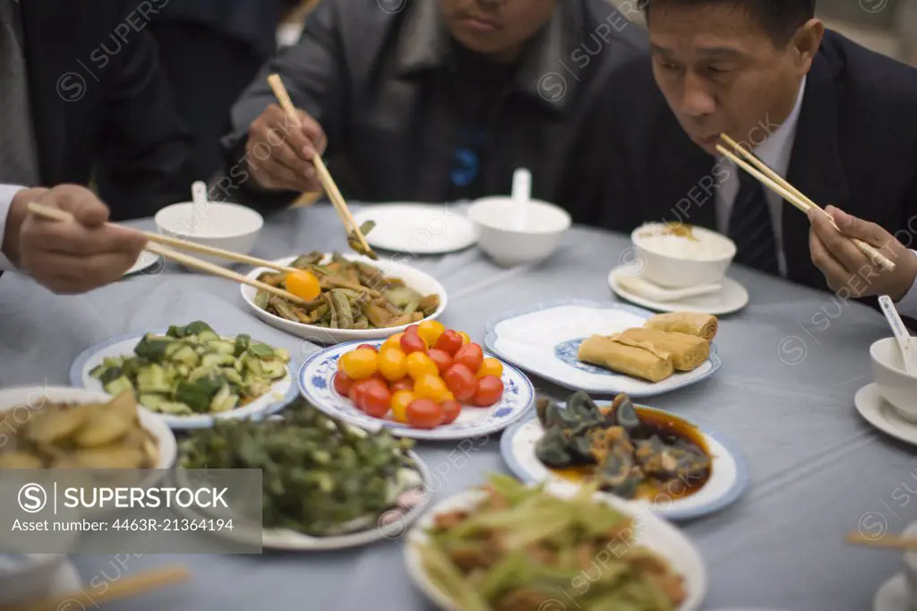 Food being eaten with chopsticks by businessmen.