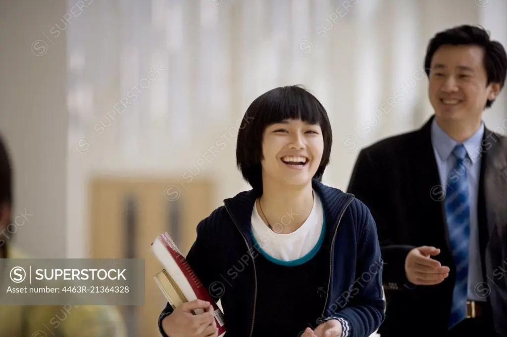 Portrait of a teenage girl standing with her mid-adult teacher in a school.