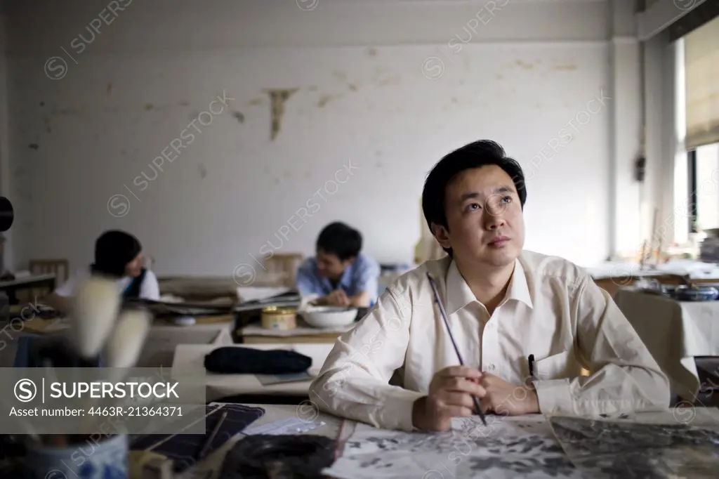 Mid-adult man painting in an art classroom.