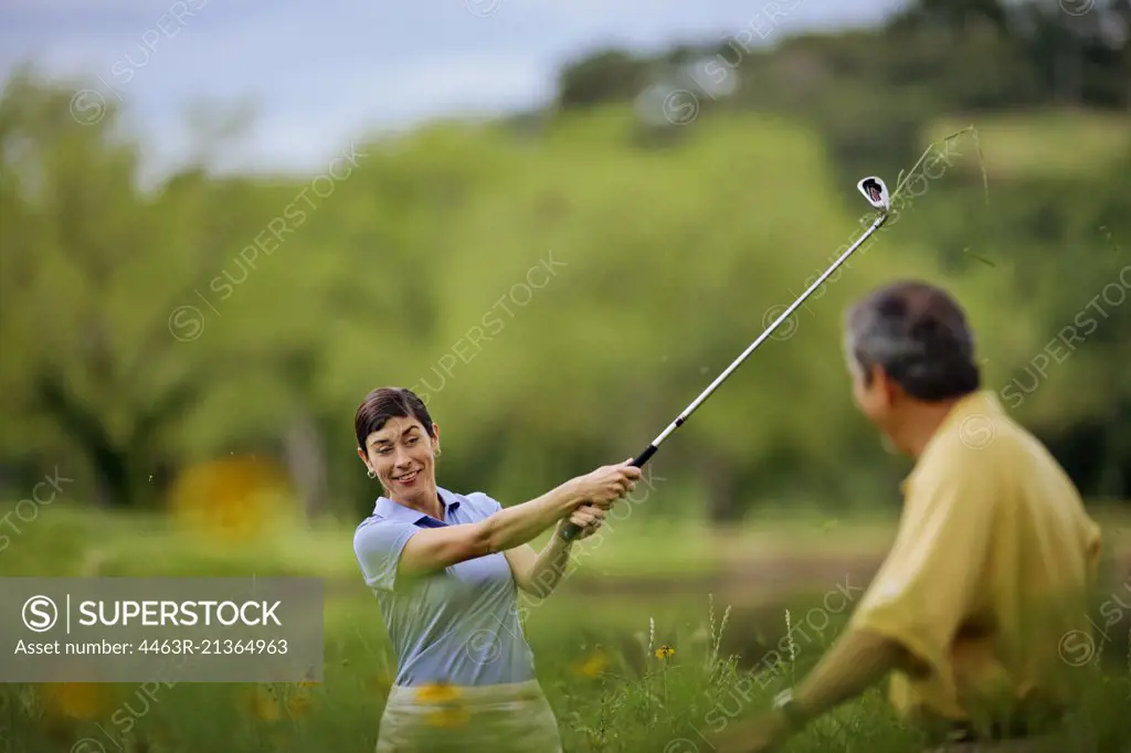 Smiling mature couple have fun playing golf together.