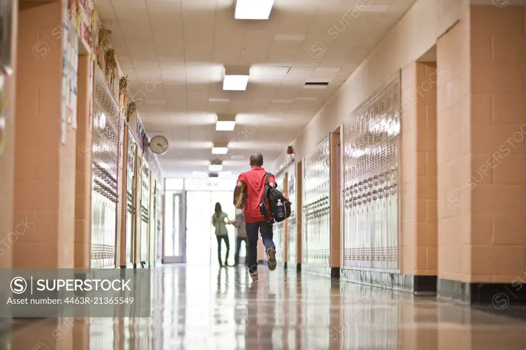 Teenage boy running towards school exit to meet friends