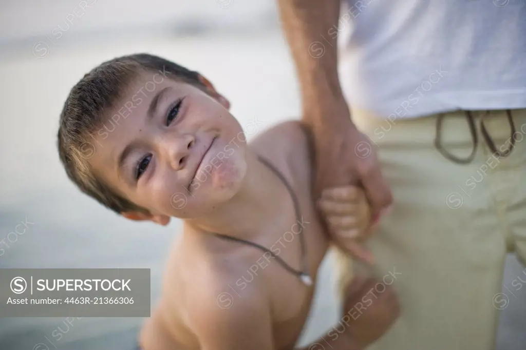 Portrait of a young boy smiling while holding his dads hand.