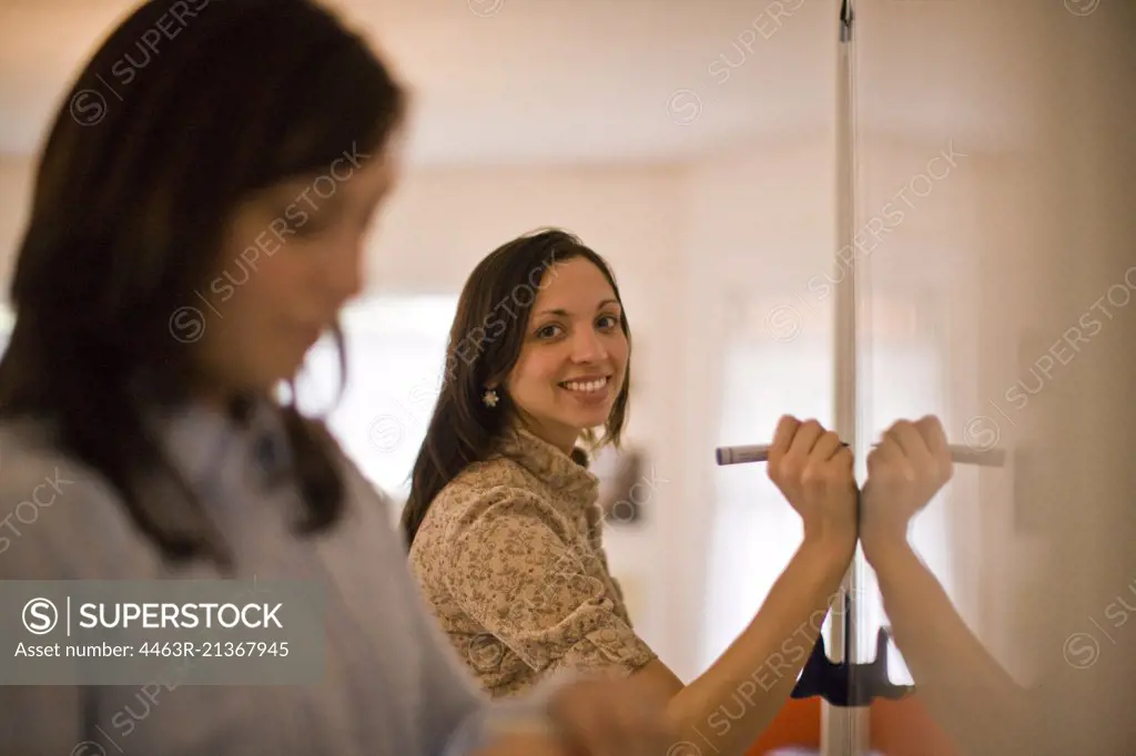 Women writing on whiteboard in classroom