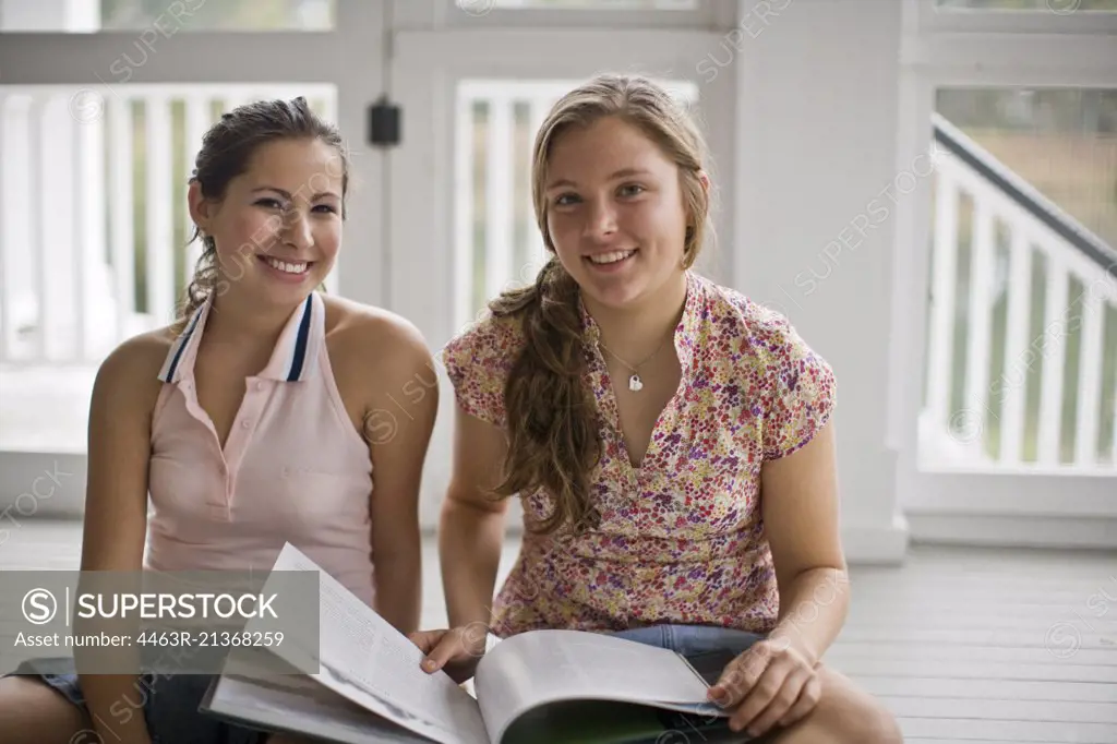 Girls reading book together on porch