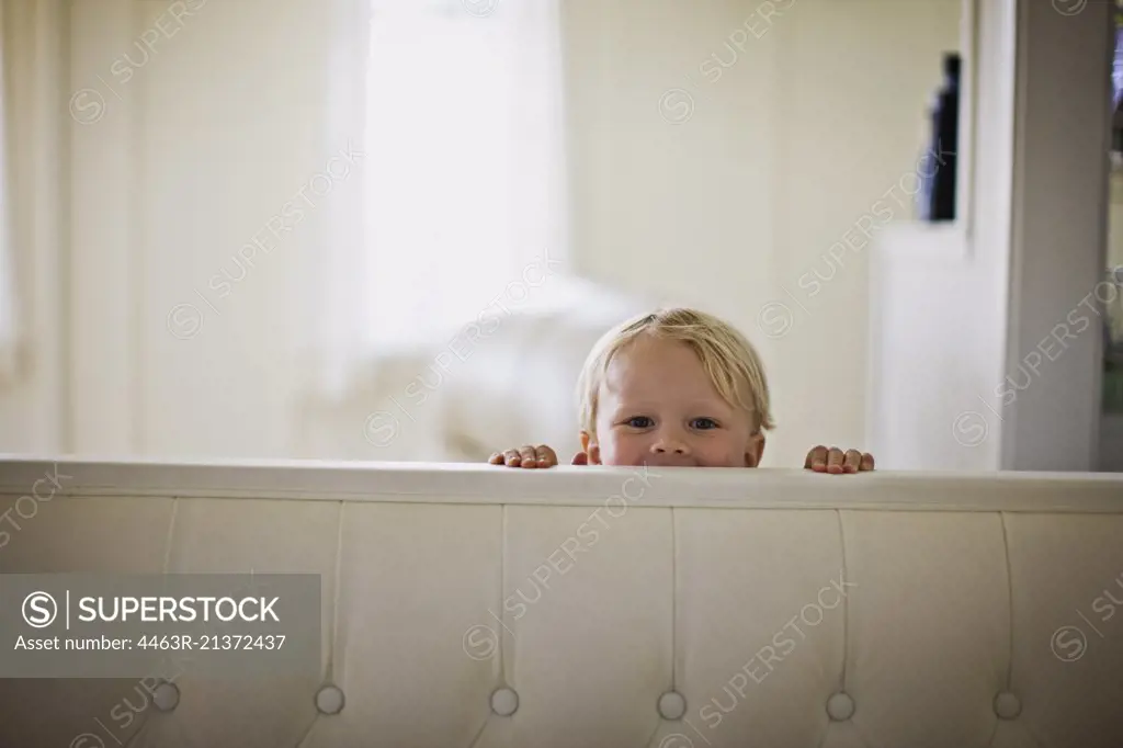 Little boy peeking over back of couch