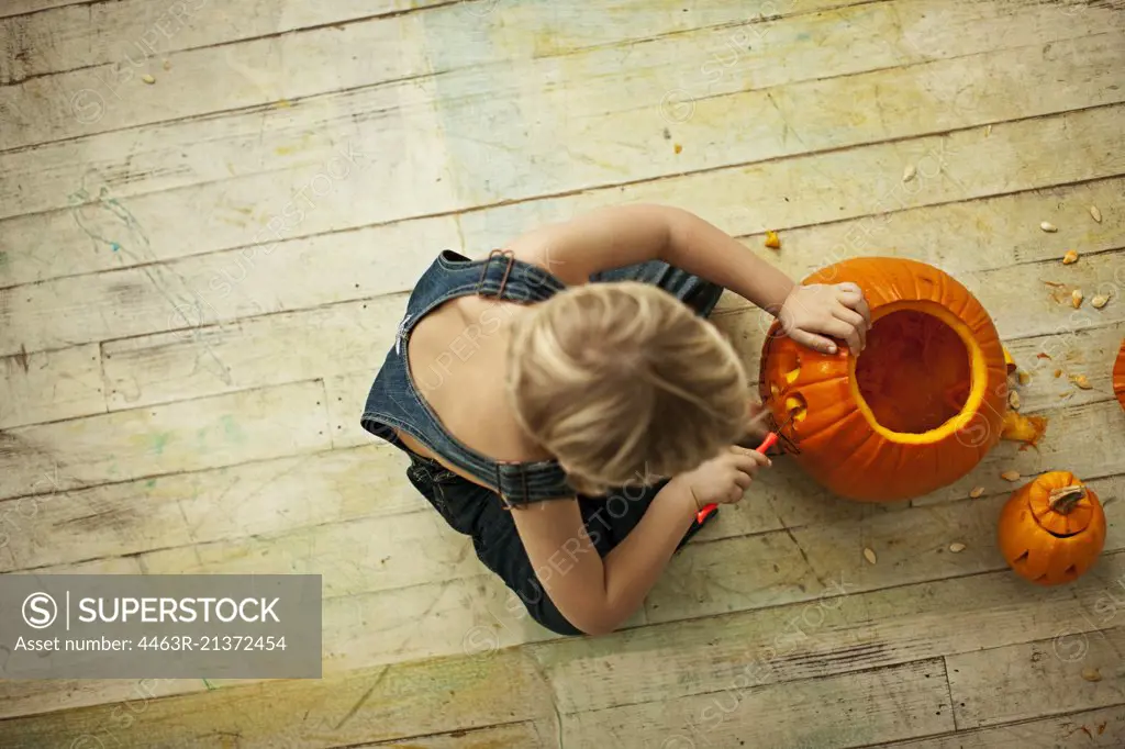 Little boy carving Halloween pumpkin