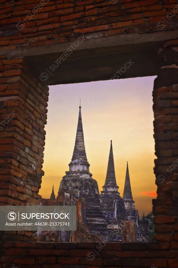 View of ancient ruin through window in a brick wall.