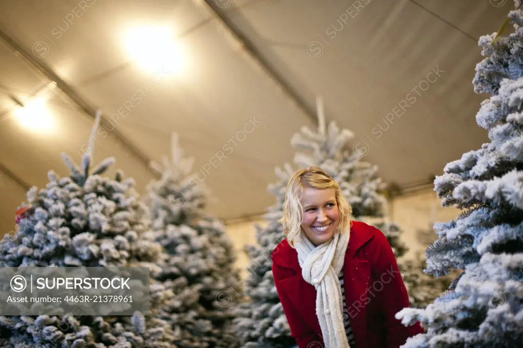 Woman playing hide and seek at a Christmas tree lot.