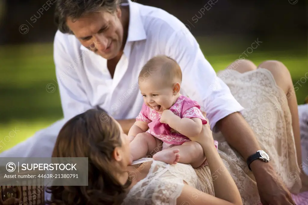 Young family lie on the grass having a picnic.