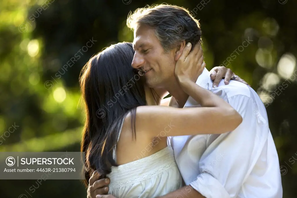 Husband and wife stand in embrace.