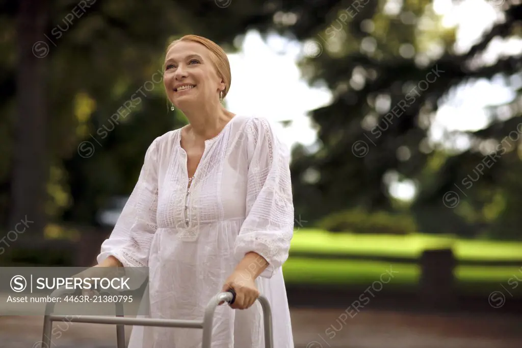 Elderly woman using a walker outdoors.