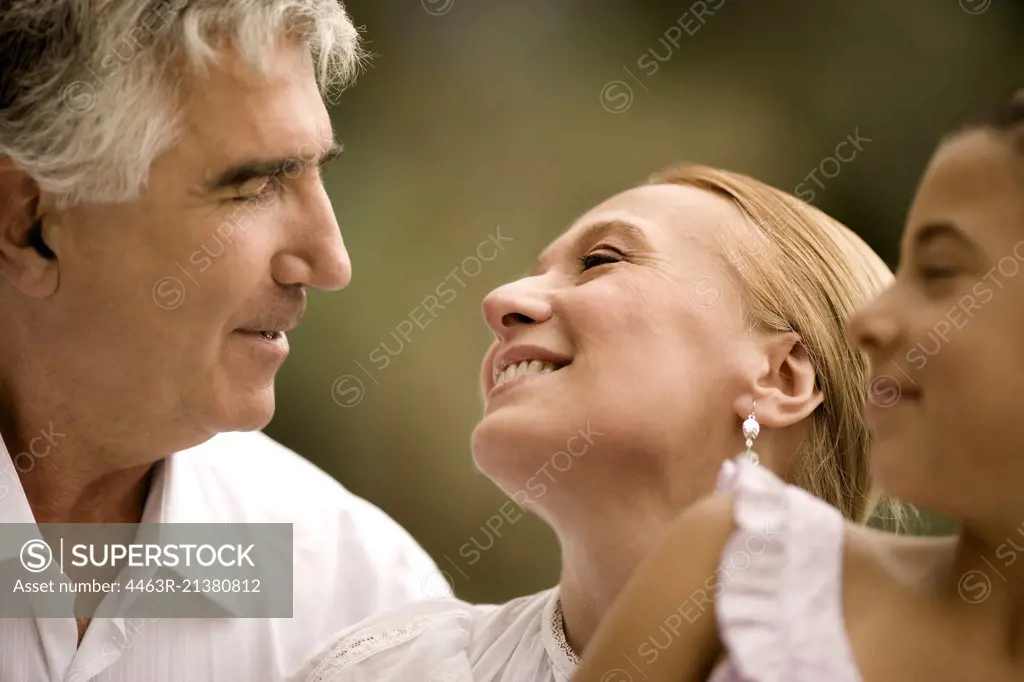 Elderly couple sit looking into each others eyes.