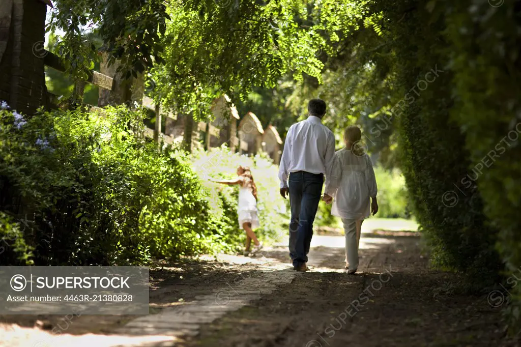 Elderly couple and their granddaughter walk down a quiet country road.