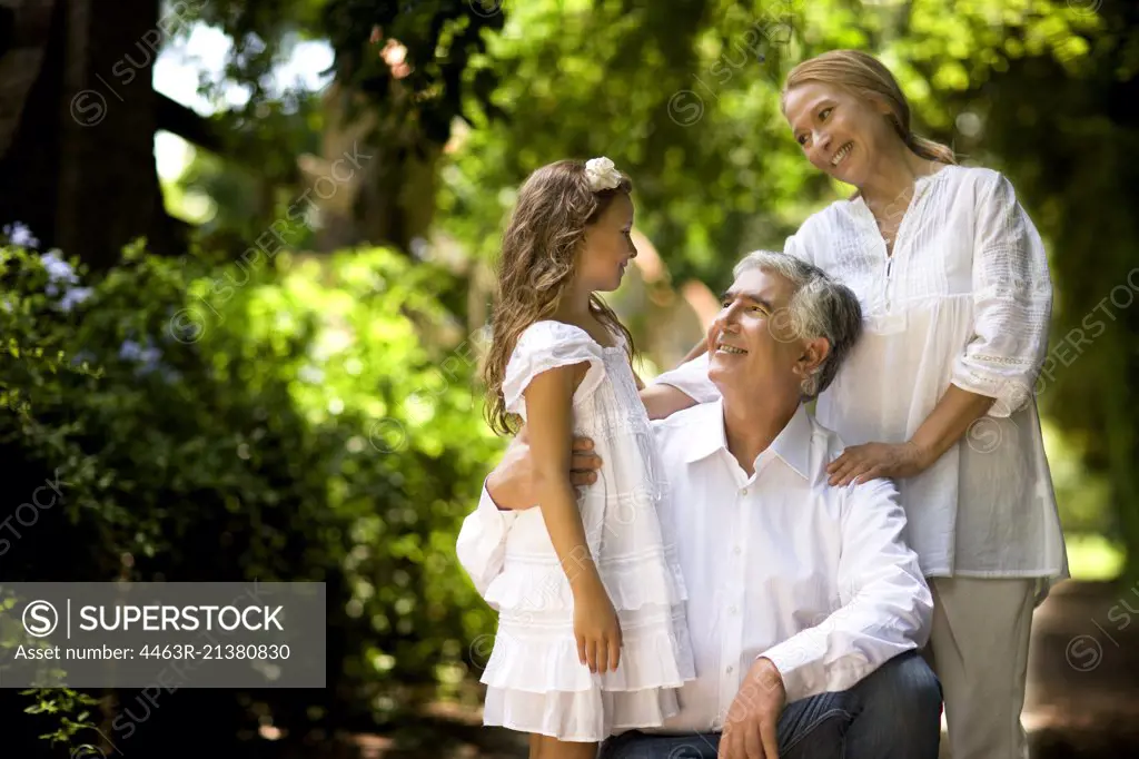 Grandparents stand with their granddaughter on a quiet country road.