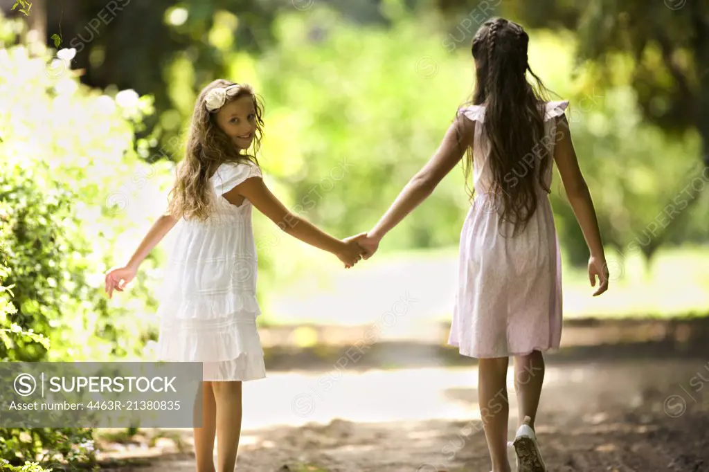 Two young girls walk down a quiet country road. 