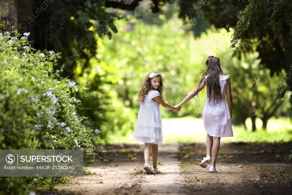 Two young girls walk down a quiet country road. 