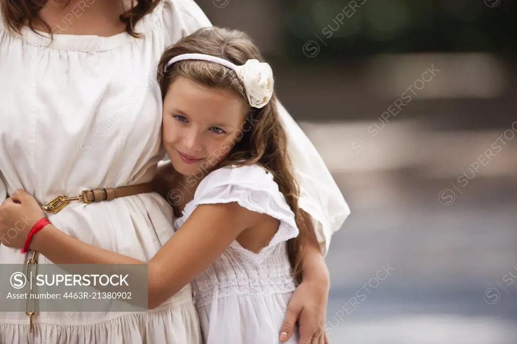 Portrait of a young girl standing beside her mother. 