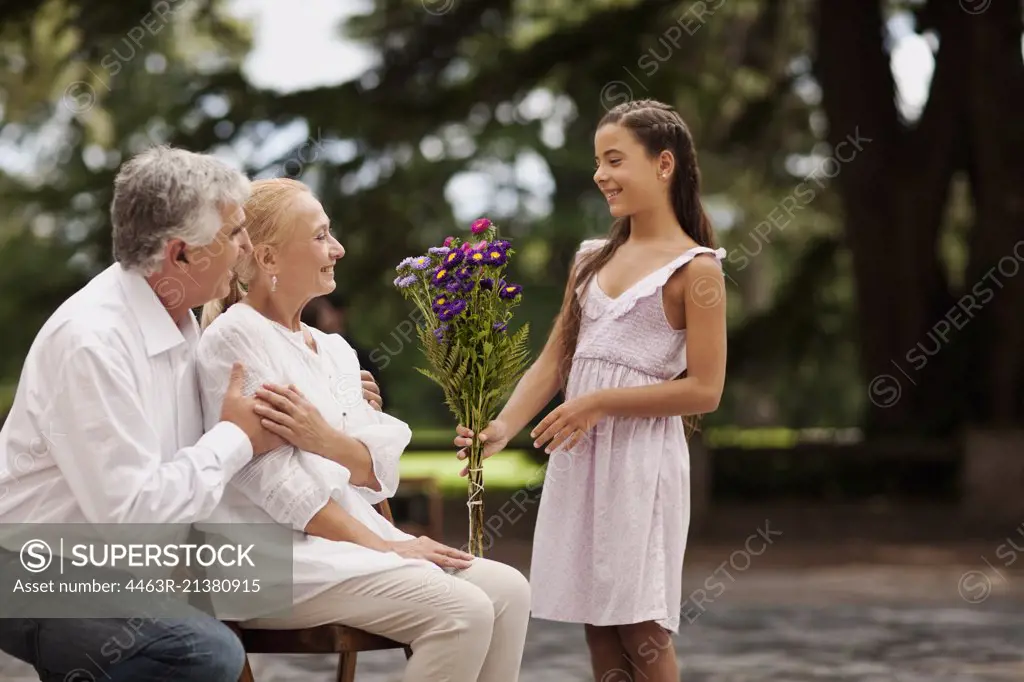 Young girl presents her grandmother with a bouquet of flowers.