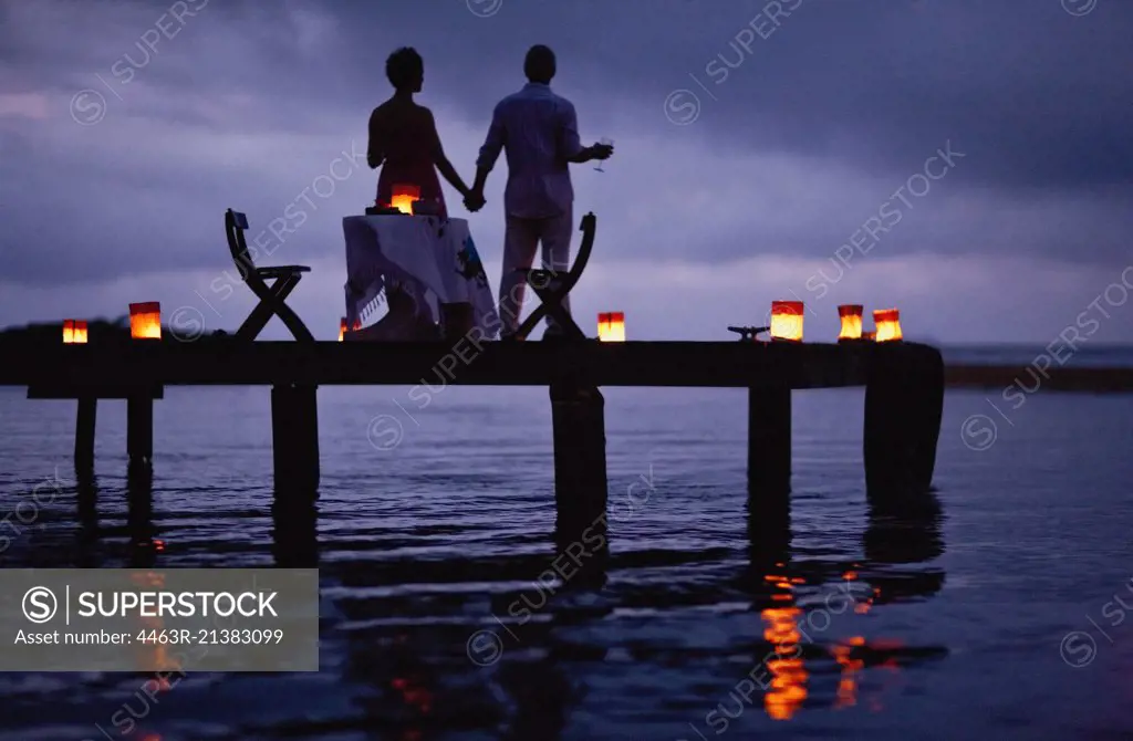 Mature couple enjoying their date on the pier at twilight.