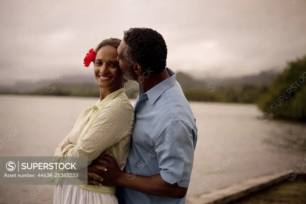 Mature man kissing his wife at the beach.