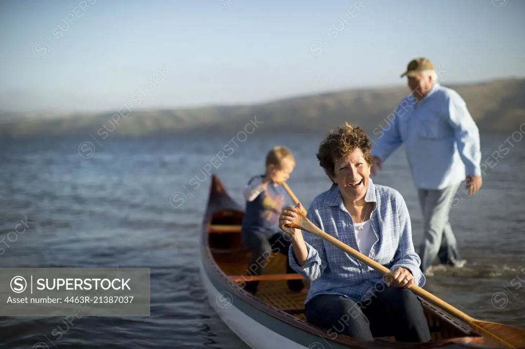 Portrait of a happy mature couple canoeing with their young grandson.