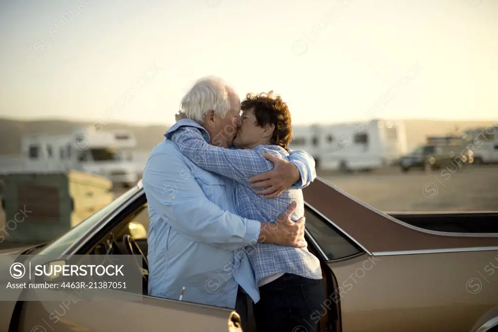 Mature couple embracing by a car.