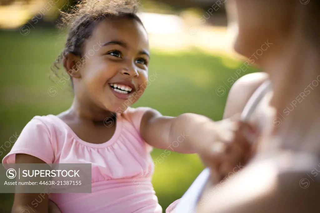 Young girl looking up at her mother and smiling.