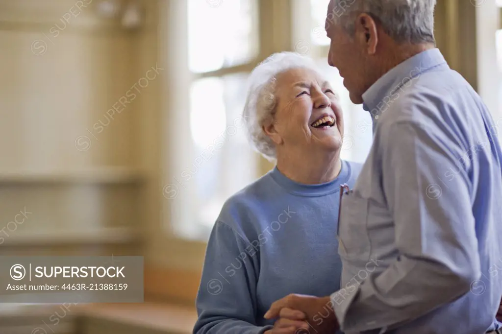 Happy senior couple dancing together in a room.