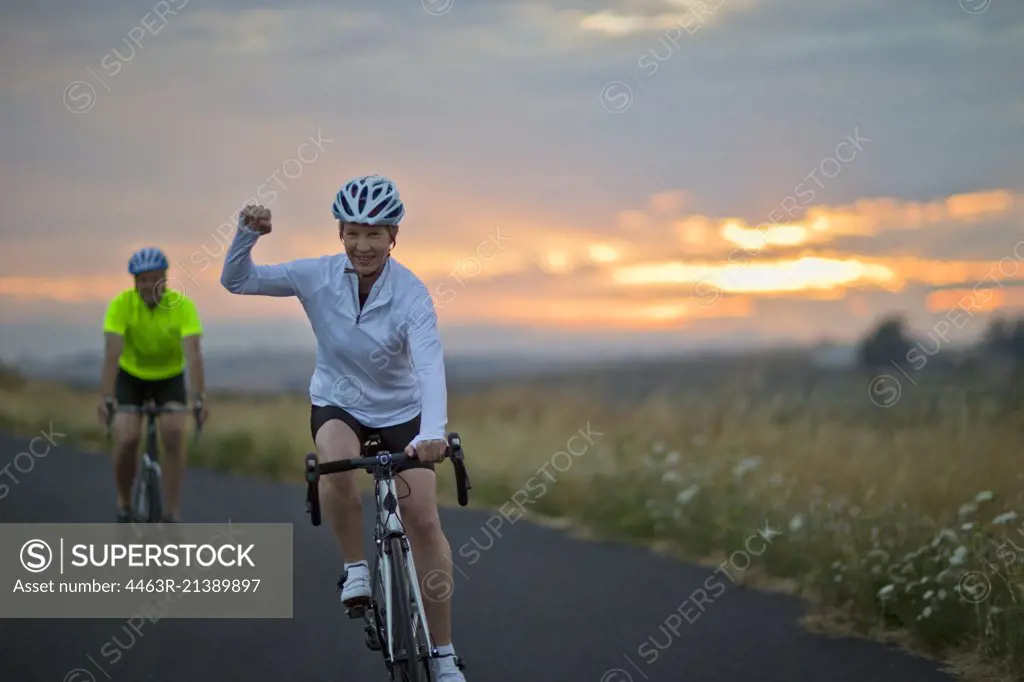 Portrait of a happy mature couple cycling along a country road.