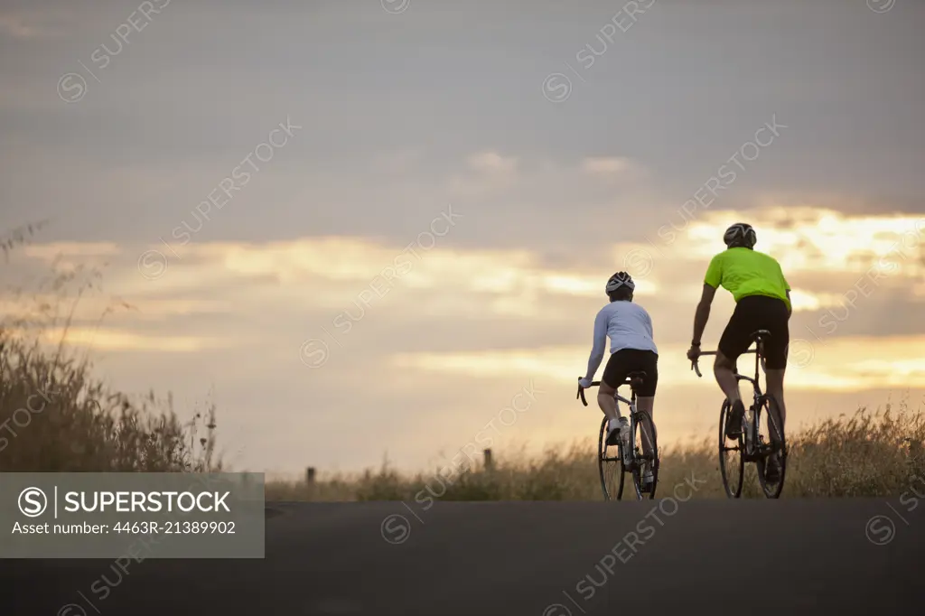 Mature couple cycling along a country road.