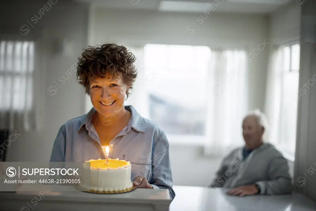 Portrait of a smiling mature woman holding a birthday cake.