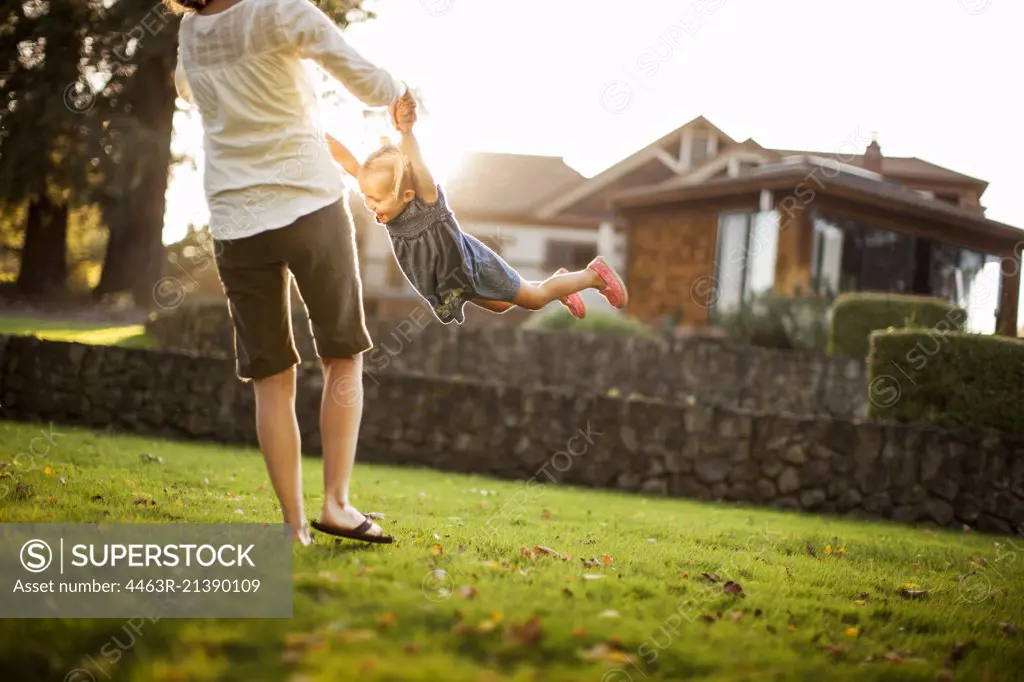 Young woman playfully spinning her happy young daughter around.