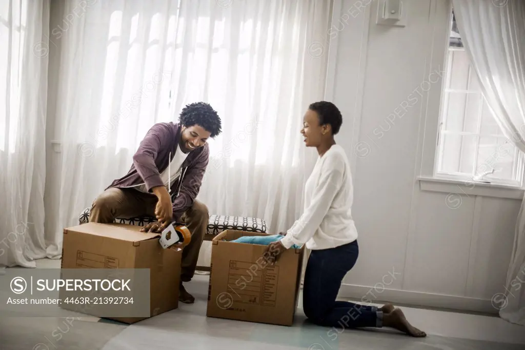 Happy couple packing boxes for a move.