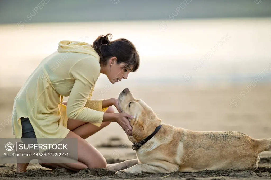 Mid adult woman playing with her dog at the beach.