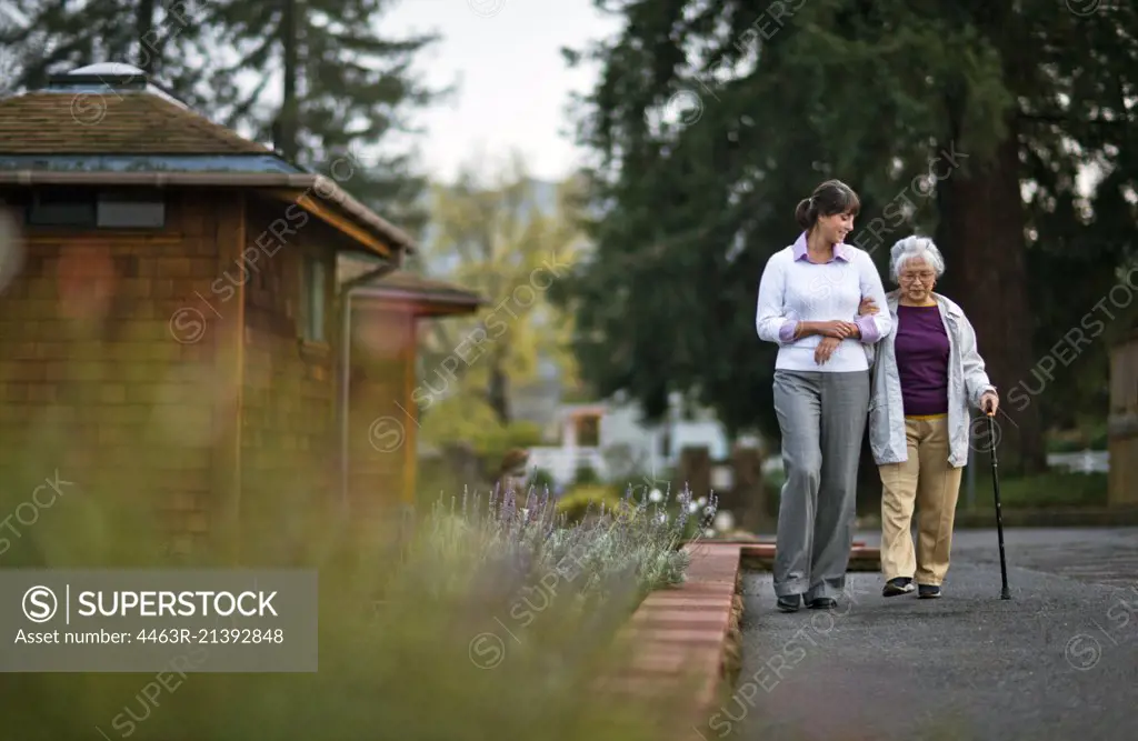 Elderly woman walking arm in arm with her doctor.