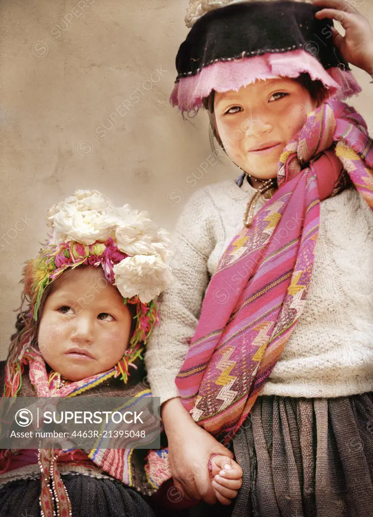 A young girl smiles holding her sisters hand.