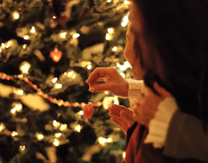 Mother and daughter hanging decorations on a Christmas tree