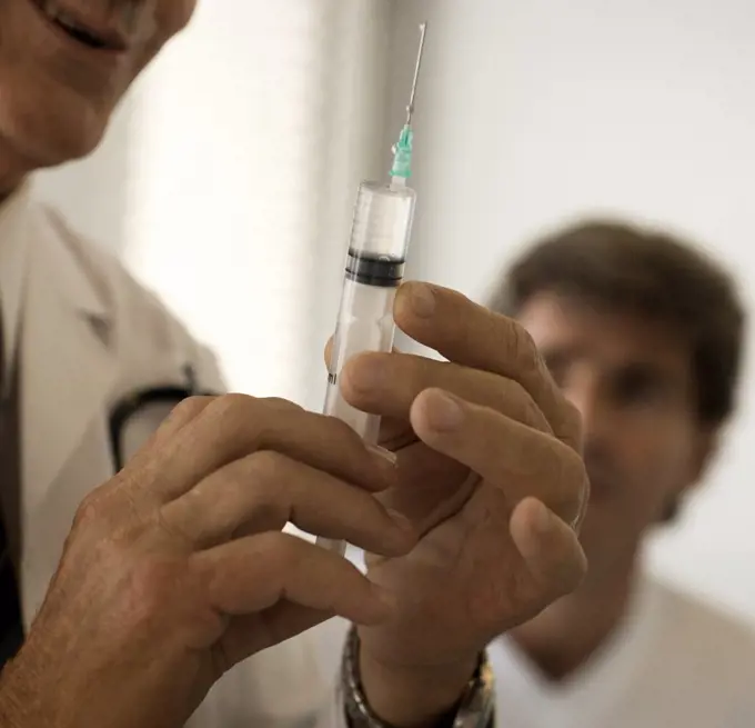 Cropped view of a doctor holding a syringe in his hand.