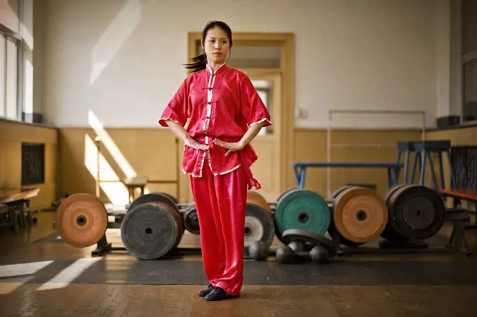 Teenage girl performing martial arts in a gym.