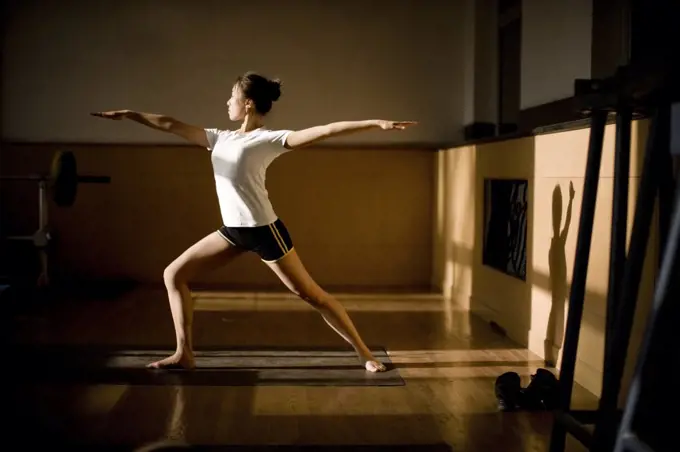 Teenage girl doing yoga in a gym.