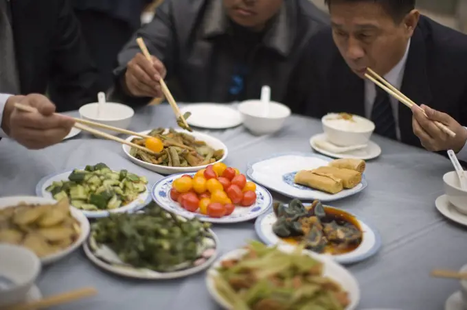 Food being eaten with chopsticks by businessmen.