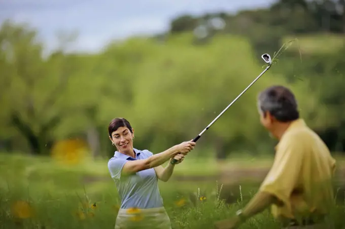 Smiling mature couple have fun playing golf together.