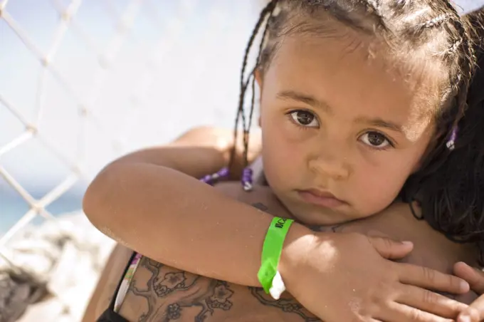 Portrait of a serious young girl getting a hug from an adult.