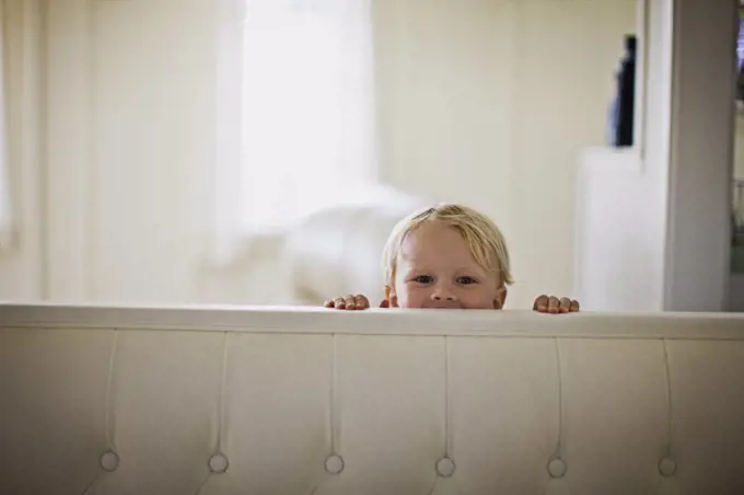 Little boy peeking over back of couch