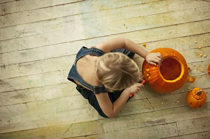 Little boy carving Halloween pumpkin