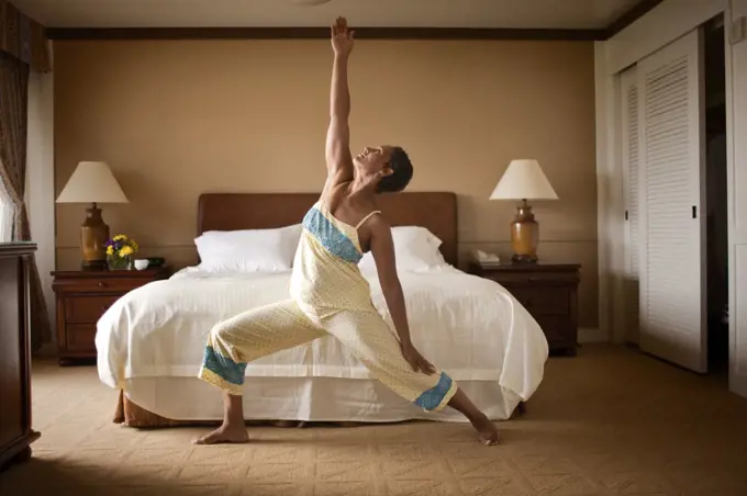 Mature woman doing yoga in bedroom